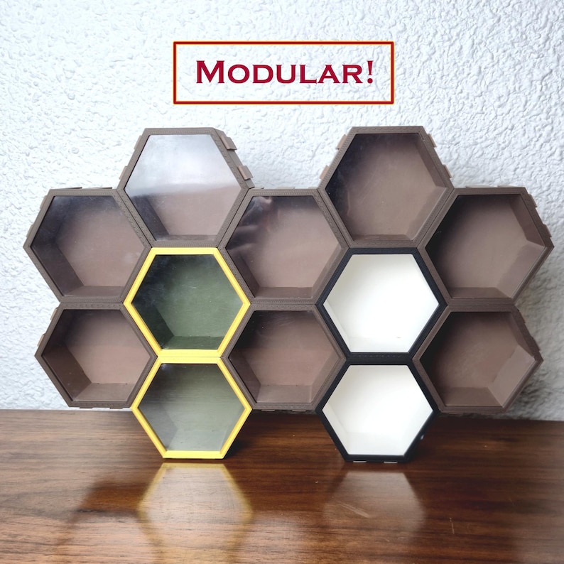 May include: Modular honeycomb-shaped shelves in a brown finish, with some cells highlighted in yellow and white. The word "MODULAR!" is displayed in a red rectangle above the shelves. The shelves are arranged on a wooden surface.