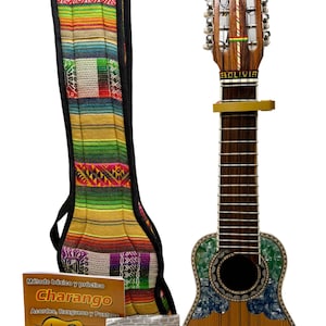 Könnte beinhalten: Ein Charango, ein kleines Anden-Saiteninstrument, mit einem Holzkörper und einer farbenfrohen, gemusterten Hülle. Ein Stimmgerät und ein Kapodaster sind angebracht. Ein Buch und eine Tüte Charango-Saiten sind ebenfalls enthalten.