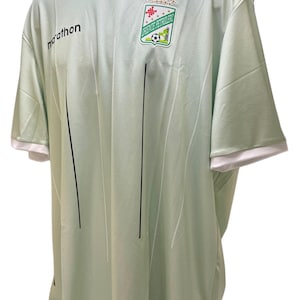 May include: Light green soccer jersey with white and black accents. The jersey features a V-neck, short sleeves, and a team logo on the chest. The word "marathon" is printed on the front.