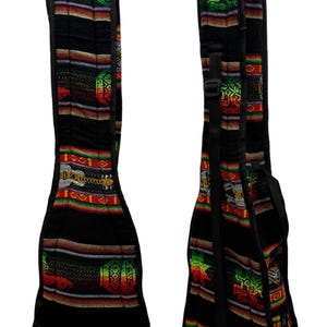 Könnte beinhalten: Zwei schwarze Ukulelenkoffer mit farbenfrohen Webstoffdesigns. Die Koffer haben eine rechteckige Form mit abgerundetem Boden und Schultergurt. Der Stoff weist geometrische Muster in Rot, Grün, Gelb und Orange auf.
