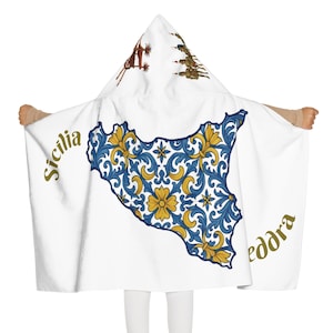 Può includere: Accappatoio bianco con cappuccio con un design floreale blu e giallo a forma di Sicilia. La parola "Sicilia" e "eddra" sono stampate in oro. Il cappuccio presenta illustrazioni marroni e dorate.