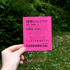 May include: A pink card with black text that reads "SO SAID I, and with me are THREE GODS, within whom are waiting night and day, little items, Heaven could not hold them all - and yet I hold - They all are sealed in one, and mean to move still's it be for my promise - ETERNITY! - Emily Bronte"