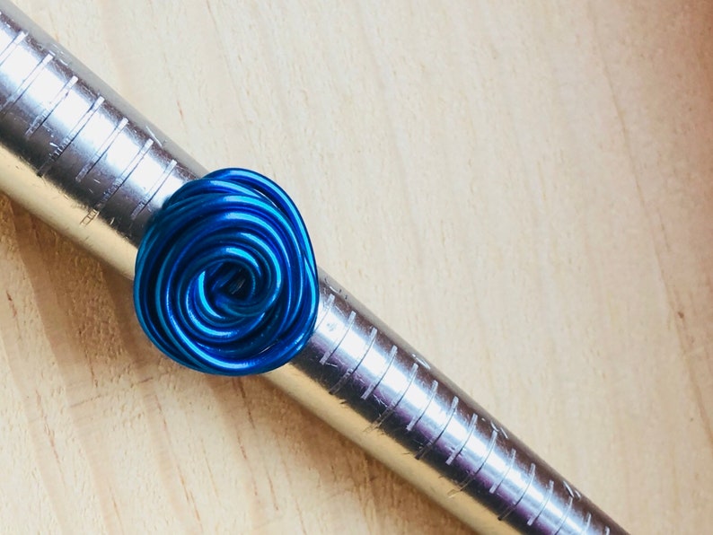 K&ouml;nnte beinhalten: Ein blauer Drahtring, der zu einer Spirale geformt ist, wird auf einem Metall-Ringma&szlig; angezeigt.