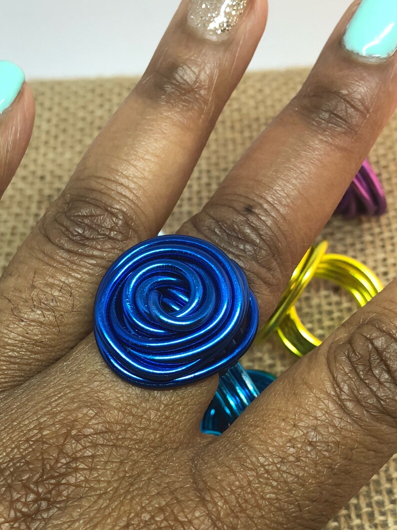 K&ouml;nnte beinhalten: Ein blauer Drahtring mit Rosenmuster. Der Ring besteht aus Draht, der zu einer Spirale gewickelt wurde.