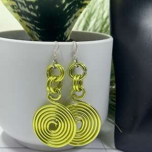 May include: A pair of lime green earrings with a spiral design. The earrings are made of wire and have a silver hook.