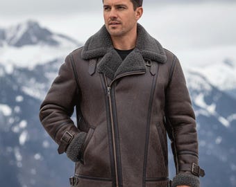 May include: A brown shearling jacket with a gray shearling collar and lining. The jacket features a diagonal zipper, two front pockets, and buckle details on the sleeves. The background shows a mountain range.