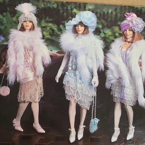 Puede incluir: Tres muñecas vestidas con vestidos de estilo flapper con flecos de cuentas y envolturas de piel. Las muñecas llevan sombreros y llevan bolsos.