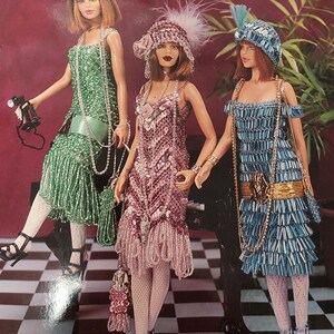 Puede incluir: Tres trajes de muñeca flapper con cuentas, en verde, rosa y azul. Las muñecas llevan sombreros y sostienen carteras. La imagen es de un libro de patrones de trajes de colección de crochet.