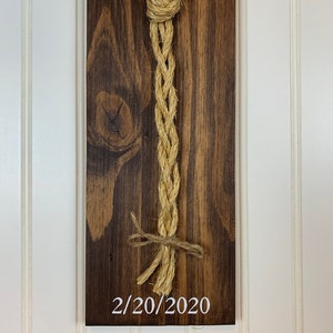 May include: A wooden sign with a white heart design and a rope tied in a knot. The date 2/20/2020 is written on the sign.