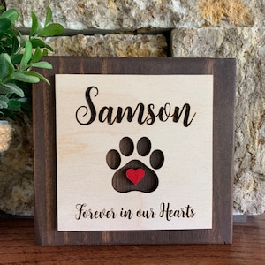 May include: Wooden sign with a paw print cutout and a red heart in the center. The sign reads "Samson Forever in our Hearts".
