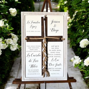 May include: A white wooden sign with a brown rope cross in the center. The sign has the text "La Familia Lopez 14 de Abril de 2025" on the top left and "Jessica & Diego" on the top right. The sign also has the text "Uno solo puede ser vencido, pero dos pueden resistir. La Cuerda de Tres Hilos No se rompe facilmente. Eclesiastes 4:12" on the left and "Asi que no son ya mas dos, sino una sola carne; por tanto, Lo Que Dios Junto, no lo separe el hombre. Mateo 19:6" on the right.