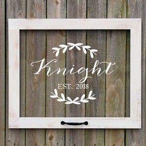 May include: White wooden frame with a black metal handle. The frame has a clear glass insert with a white vinyl decal that reads "Knight EST. 2018" with a wreath of leaves around the text.