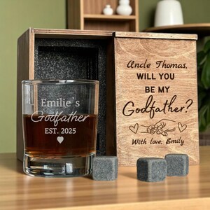 May include: A personalized whiskey glass with the text "Emilie's Godfather EST. 2025" inside a wooden box. The box lid is engraved with "Uncle Thomas, WILL YOU BE MY Godfather? With love, Emily." Includes three gray whiskey stones.