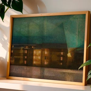 Op de afbeelding: Een ingelijste rechthoekige print met een abstracte weergave van een gebouw in de nacht. Het kunstwerk toont een donkergroenblauwe lucht boven een bouwwerk met verlichte goudgele ramen, geplaatst in een lichtgekleurde houten lijst.