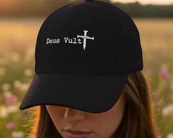 以下が含まれることがあります： 黒の野球帽で、白い刺繍でDeus Vultと書かれたテキストと、その文字の右側に配置された2本の釘が交差して十字架を形成している白いグラフィックが、帽子のフロントパネルに施されています。
