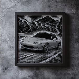 May include: Framed grayscale artwork of a silver convertible sports car on a winding road. The car is depicted in motion, with a backdrop of trees and mountains. The artwork is encased in a black frame, mounted on a textured gray wall.