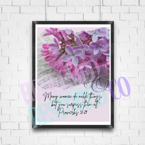 May include: A printable wall art design featuring a floral arrangement of purple and white flowers with a bible verse quote: "Many women do noble things, but you surpass them all. Proverbs 31:29"
