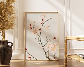 Könnte beinhalten: Ein gerahmter Kunstdruck mit einer Aquarellillustration eines blühenden Zweigs mit weißen und rosa Blüten und roten Akzenten. Das Kunstwerk wird in einem Raum mit einer Vase mit getrockneten Pflanzen und einer Bambusbank ausgestellt.