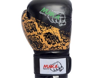 May include: Black and gold boxing glove with the text "MUKKA Sports" and a fist logo. The glove features a textured gold pattern on the front and a black wrist strap with the brand name and logo. The glove is labeled "16oz".