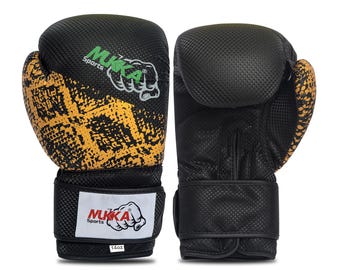 May include: Pair of black and gold boxing gloves with the brand name "MUKKA Sports" visible. The gloves have a textured design on the black areas and a gold, patterned design on the striking surface. The gloves are 14oz.