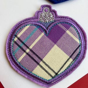Può includere: Ornamento a forma di cuore a quadri viola con una parte superiore argentata. L'ornamento presenta un motivo a quadri crema, viola e verde acqua, delineato con cuciture verde acqua e viola. Per decorazioni natalizie.