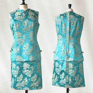 May include: A sleeveless turquoise dress with a gold floral pattern. The dress has a fitted bodice and a skirt that falls to the knees.