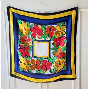 May include: A square silk scarf with a floral pattern. The scarf has a white central square with a yellow border, surrounded by red, yellow, and brown flowers with green leaves. It has a blue, yellow, and black border.