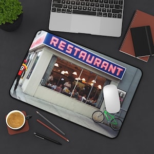 May include: A mousepad featuring a vintage diner with a neon "RESTAURANT" sign, a green bicycle, and a person in the window.