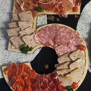 Peut inclure: Un plateau de service en bois en forme de chiffre cinq, garni d'un assortiment de charcuteries tranchées, incluant du salami, du chorizo et du prosciutto, ainsi que des tranches de pâté, décoré de tomates cerises fraîches et de persil.