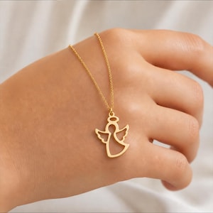 K&ouml;nnte beinhalten: Eine goldfarbene Engels-Anh&auml;nger-Halskette. Der Anh&auml;nger ist ein Ausschnitt eines Engels mit Heiligenschein und Fl&uuml;geln. Die Halskette wird auf einer Hand pr&auml;sentiert.