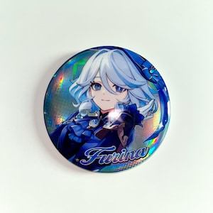 Pu&ograve; includere: Un bottone rotondo con sfondo olografico raffigurante un personaggio con capelli azzurri e abiti blu. Il nome del personaggio, Furina, &egrave; scritto in blu in corsivo. Il bottone ha una superficie lucida e riflettente.
