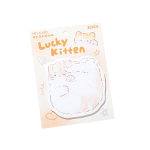 Puede incluir: Un paquete de 30 notas adhesivas con forma de gato. Las notas son blancas con un dise&ntilde;o de acuarela naranja claro y una linda ilustraci&oacute;n de gato. El paquete tiene las palabras "Lucky Kitten" en naranja y "cute" en letras peque&ntilde;as.