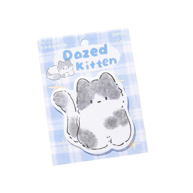 Puede incluir: Un paquete de 30 blocs de notas adhesivos con un dise&ntilde;o de gato de dibujos animados. El gato es blanco con manchas grises y una cabeza gris. Los blocs de notas est&aacute;n sobre un fondo azul claro con un patr&oacute;n de cuadr&iacute;cula, y el texto "Dazed Kitten" es visible.