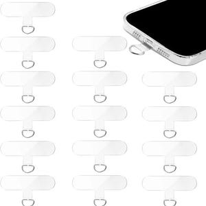 May include: Clear phone lanyard patches with metal rings. The patches are rectangular with a small loop for attaching a lanyard. One phone is shown with a patch inserted into the charging port.