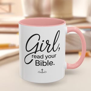 May include: White ceramic mug with a pink interior and handle. The mug features the text "Girl, read your Bible" in black script, along with a small cross icon. A simple and elegant design.