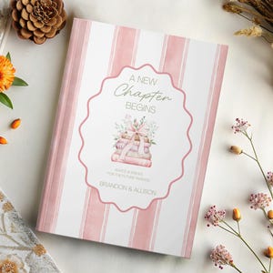 Puede incluir: Un diario de tapa dura con una cubierta a rayas rosas y blancas. El centro presenta un marco decorativo con el texto "A New Chapter Begins" y una pila de libros con un lazo. Los nombres "Brandon & Allison" están impresos en la parte inferior.