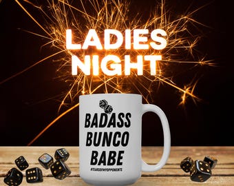 May include: A white ceramic mug with the text "BADASS BUNCO BABE" in black, along with dice graphics. The mug is on a wooden surface with scattered dice. The words "LADIES NIGHT" are in bright letters above the mug, with a sparkler effect in the background.