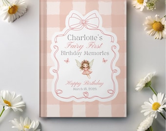 May include: A personalized fairy-themed birthday memory book. The cover is light pink with a gingham pattern and a decorative label featuring a fairy illustration, the name "Charlotte's", and the date "March 18, 2026". Daisies surround the book.