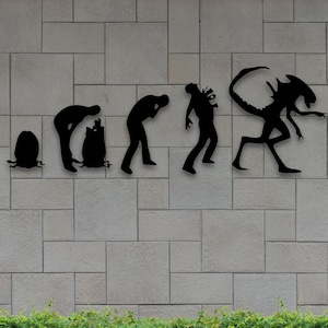 May include: Black metal wall art depicting the evolution of a creature, from egg to alien. The silhouette art is mounted on a light gray brick wall, with green foliage at the bottom. The image includes file type abbreviations.