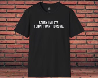 Op de afbeelding: Zwart T-shirt met de witte tekst "SORRY I'M LATE. I DIDN'T WANT TO COME." Het shirt wordt getoond tegen een bakstenen muur. Het heeft korte mouwen en een ronde hals.