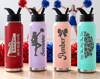 May include: Four stainless steel water bottles with black lids and straws. The red bottle features a megaphone and the name Kimber. The lavender bottle shows a cheerleader silhouette and the name Susanne. The peach bottle displays a bow and the name Amber. The teal bottle has a pom-pom graphic and the name Sarah.
