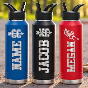 May include: Three stainless steel water bottles with black lids and straws. The blue bottle features an arrow with CC and the name NAME. The black bottle features an arrow with XC and the name JACOB. The red bottle features a winged shoe and the name MEGAN.