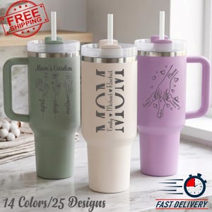 May include: Three insulated tumblers with handles and straws in sage green, cream, and lavender. The green tumbler features floral designs and names. The cream tumbler displays the word MOM with names. The lavender tumbler shows hand illustrations.