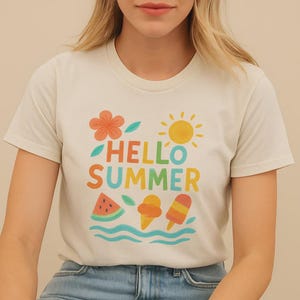 Puede incluir: Camiseta color crema con un gráfico colorido de "Hello Summer". El diseño incluye una flor, un sol, una rodaja de sandía, un cono de helado y un polo. La camiseta está hecha de un material suave.