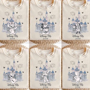 May include: Cream-colored t-shirts featuring Disney characters and a castle design. Each shirt has a different character: Stitch, Mickey Mouse, Minnie Mouse, Olaf, Buzz Lightyear, and Winnie the Pooh. The text "Disney Trip 2026" is printed below the castle.