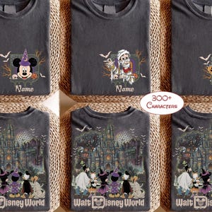 May include: A collection of charcoal gray t-shirts featuring Disney-themed Halloween graphics. Some shirts display individual characters like Mickey Mouse, a mummy, or a witch, while others show a group of characters before a haunted castle.