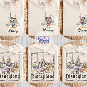 May include: Six off-white t-shirts featuring Disney character graphics. The top row shows individual characters with text reading Daddy, Mommy, and Custom. The bottom row displays a group of characters with the text Disneyland Paris.