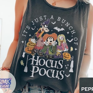May include: A charcoal gray sleeveless tank top featuring a graphic print of three cartoon characters dressed as witches, surrounded by pumpkins, bats, and ghosts. The text reads, IT'S JUST A BUNCH OF HOCUS POCUS, in a distressed white font.