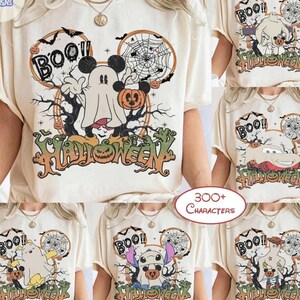 Peut inclure: Un t-shirt &agrave; manches courtes de couleur cr&egrave;me avec une impression graphique repr&eacute;sentant un fant&ocirc;me portant des oreilles de souris, une toile d'araign&eacute;e, une citrouille et le texte "BOO!!" et "HALLOWEEN". Le motif inclut des arbres noirs.