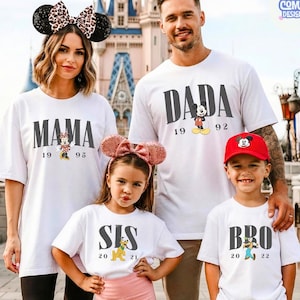 K&ouml;nnte beinhalten: Eine Familie in passenden wei&szlig;en T-Shirts mit schwarzem Text und Disney-Charaktergrafiken. Die Shirts tragen die Aufschrift "MAMA", "DADA", "SIS" und "BRO", mit den Jahren 1995, 1992, 2021 und 2022. Die Familie steht vor einem Schloss.